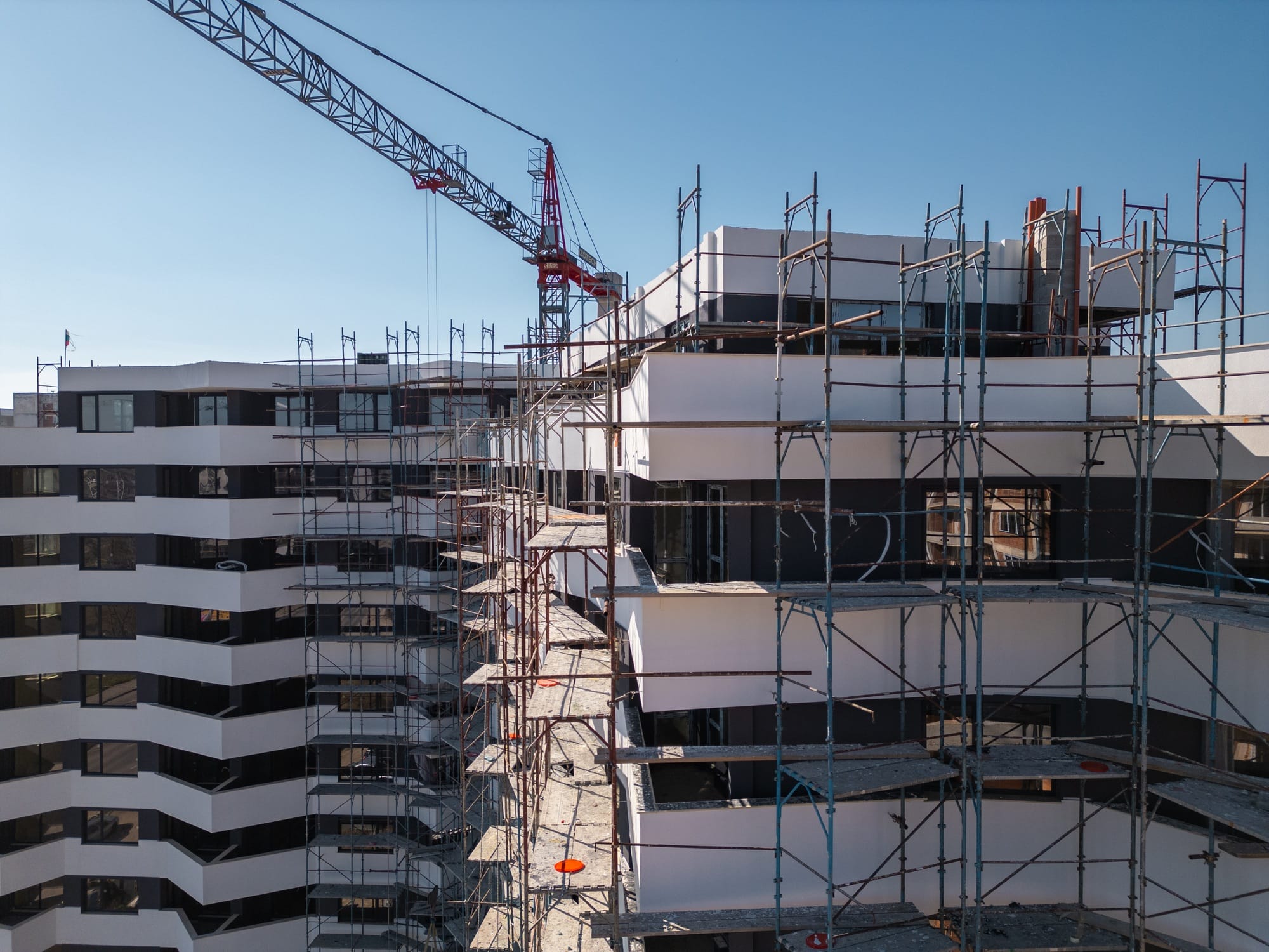 Construction progress of a modern residential building with scaffolding in a bustling urban area